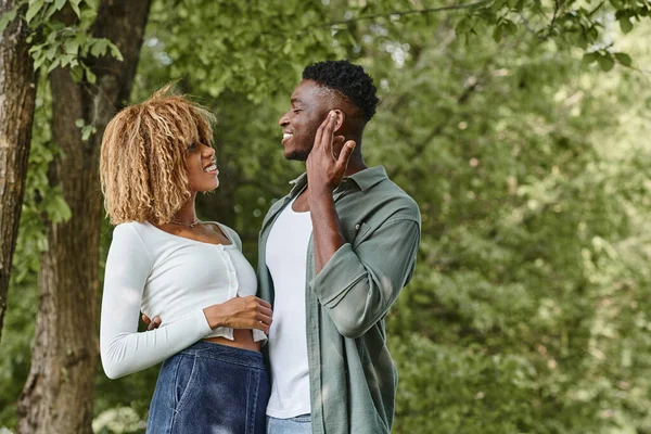 Lenguaje de señas, alegre pareja afroamericana comunicándose con gestos y de pie al aire libre - foto de stock