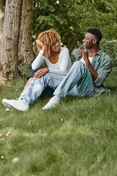 Sign language, positive african american couple communicating with gestures and sitting on grass — Stock Photo