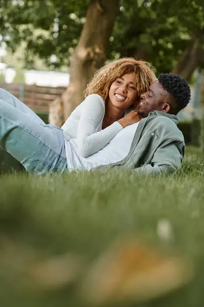 Heureux couple afro-américain ayant du temps de qualité avec l'autre tout en étant couché sur l'herbe — Photo de stock