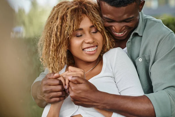 Sonriente pareja afroamericana pasar tiempo de calidad entre sí en el parque, tomados de la mano - foto de stock