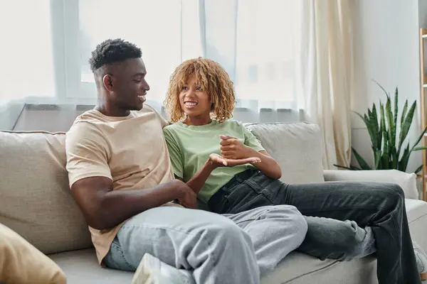 Acogedora conversación de pareja afroamericana feliz usando lenguaje de señas para la comunicación en casa - foto de stock