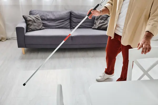 Cropped view of blind indian man in cozy everyday attire using his walking stick while in kitchen — Stock Photo