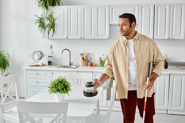 Good looking indian man with blindness using walking stick and holding coffee pot while in kitchen — Stock Photo