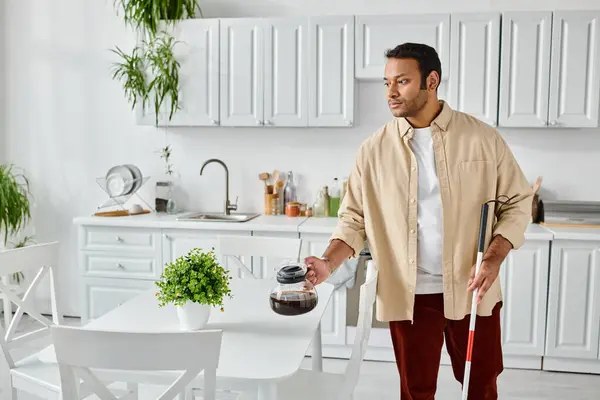 Good looking indian man with blindness using walking stick and holding coffee pot while in kitchen — Stock Photo