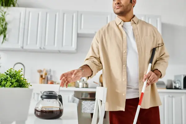 Handsome indian man with visual impairment using walking stick and holding coffee while in kitchen — Stock Photo