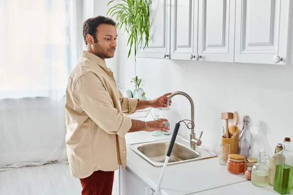 Good looking indian man with visual impairment pouring some tap water in his glass, disabled — Stock Photo