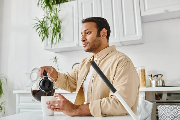 Homem indiano de boa aparência em traje casual com cegueira sentado à mesa e derramando um pouco de café — Fotografia de Stock