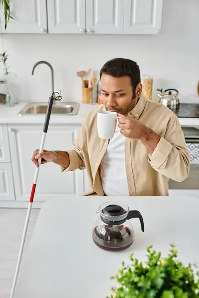 Schöner indischer Mann mit Sehschwäche sitzt und trinkt leckeren Kaffee in der Küche — Stockfoto