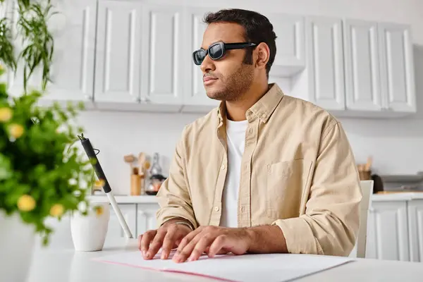 Bonito índio homem com deficiência visual em óculos leitura braille código enquanto na cozinha — Fotografia de Stock