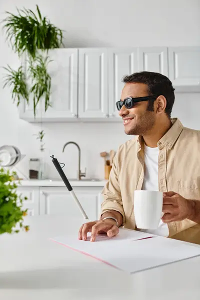 Cheerful blind indian man in casual attire with coffee and walking stick reading braille code — Stock Photo