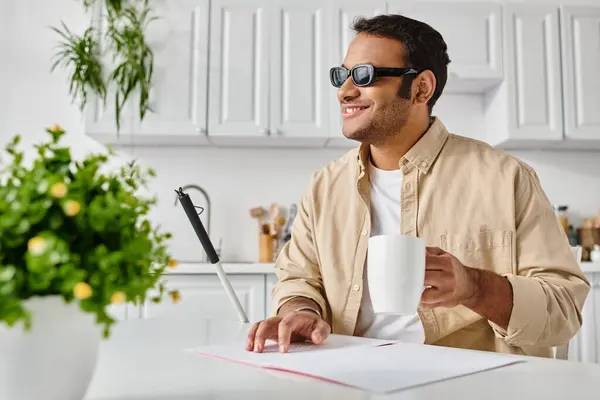 Joyous blind indian man in casual attire with coffee and walking stick reading braille code — Stock Photo