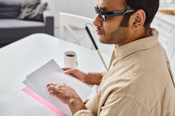 Attractive indian man with blindness in casual attire with walking stick reading braille code — Stock Photo