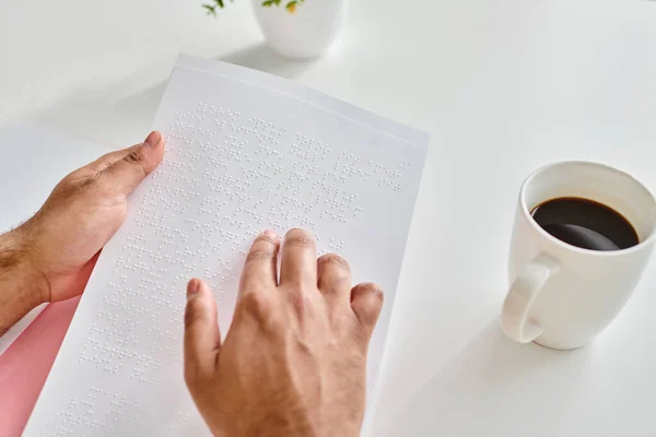 Cropped view of indian man with blindness in casual attire with coffee reading braille code — Stock Photo