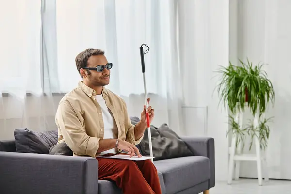 Joyful indian man with visual impairment with glasses and walking stick reading braille code — Stock Photo