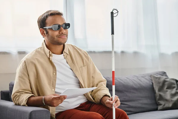 Jolly indian man with visual impairment with glasses and walking stick reading braille code — Stock Photo