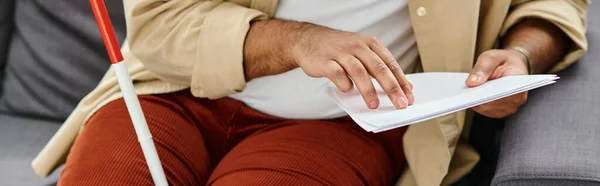 Vista cortada do homem cego indiano em roupas confortáveis sentado no sofá e lendo código braille, banner — Fotografia de Stock