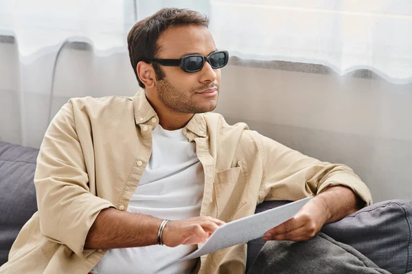 Good looking indian man with blindness in cozy outfit sitting and reading braille code at home — Stock Photo