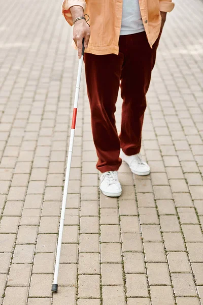 Ausgeschnittene Ansicht eines indischen Behinderten in orangefarbener Jacke mit Gehstock im Freien — Stockfoto