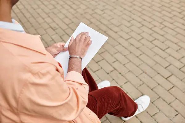 Cropped view of indian disabled man in  jacket sitting on bench and reading braille code, blind — Stock Photo