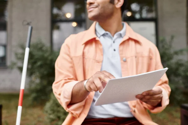 Cropped view of indian man with visual impairment in vivid jacket on bench reading braille code — Stock Photo