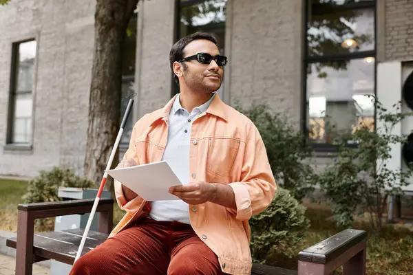 Homem índio alegre com deficiência visual com óculos sentados no banco e lendo código braille — Fotografia de Stock