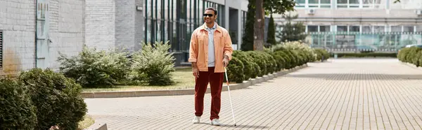 Homem cego indiano alegre em jaqueta laranja com óculos e bengala andando dando um passeio no parque, banner — Fotografia de Stock