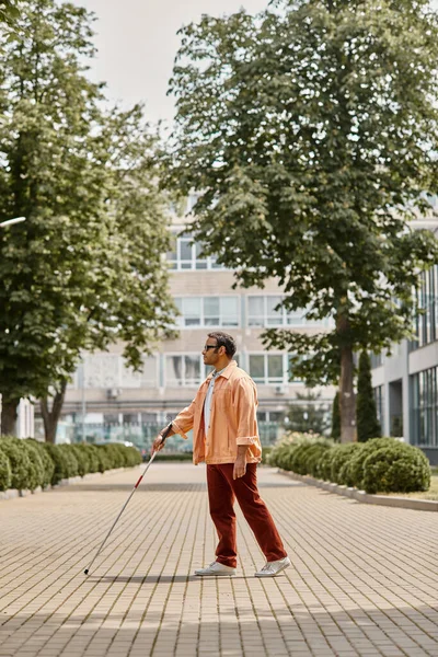 Bonito indiana cego homem em jaqueta laranja com óculos e bengala andando a pé no parque — Fotografia de Stock