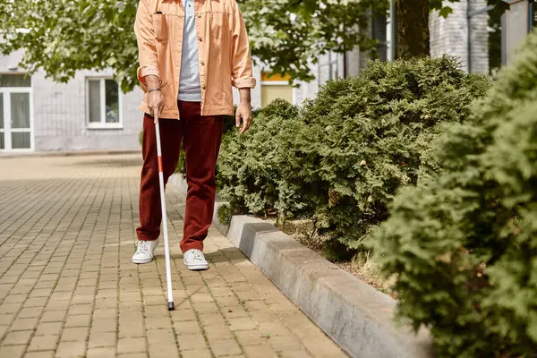 Vista ritagliata dell'uomo disabili indiano in giacca arancione con bastone da passeggio che cammina nel parco — Foto stock