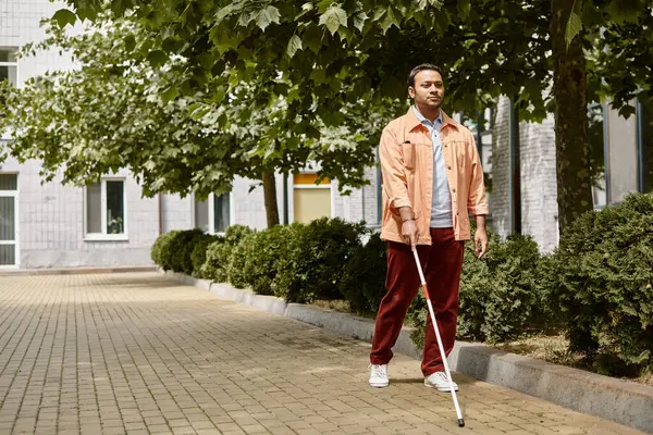 Good looking indian man with blindness in orange vivid jacket with walking stick taking walk in park — Stock Photo