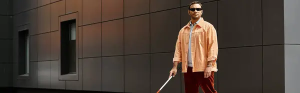 Schöner indischer Behinderter in Jacke mit Brille und Stock mit grauer Wand auf Hintergrund, Banner — Stockfoto