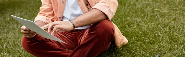 Ausgeschnittene Ansicht eines blinden indischen Mannes in pulsierender Jacke, der auf Gras sitzt und Brailleschrift-Code liest, Banner — Stockfoto