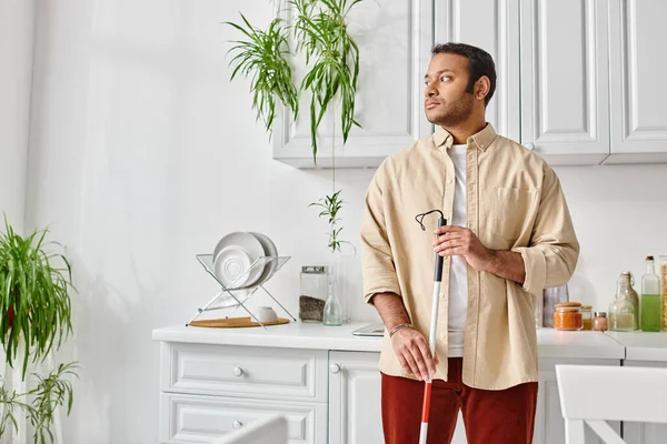 Handicapé bel homme indien dans casual confortable homewear tenant bâton de marche tandis que sur la cuisine — Photo de stock
