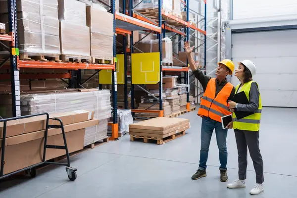 Cheerful supervisor with tablet pointing out details to female employee in a warehouse with cargo — Stock Photo