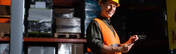 Heureux superviseur d'entrepôt d'âge moyen en chapeau dur avec presse-papiers, bannière professionnelle headshots — Photo de stock