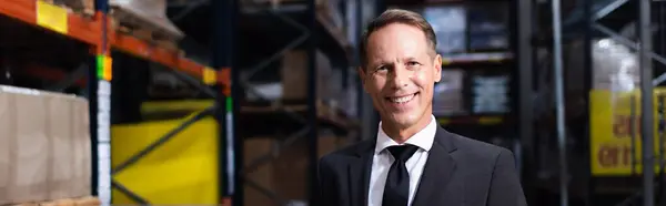 Happy middle aged businessman in suit smiling in warehouse, professional headshot banner — Stock Photo