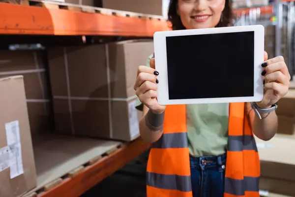 Trabalhador armazém feminino cortado e feliz em colete de segurança segurando tablet digital com tela em branco — Fotografia de Stock