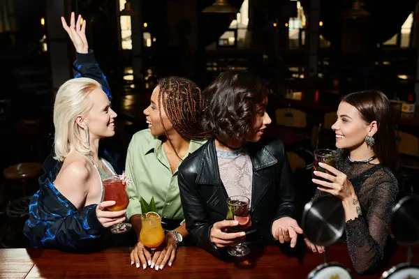 Улыбающиеся мультирасовые модники с коктейлями беседующие во время вечеринки в баре, дружба и досуг — стоковое фото