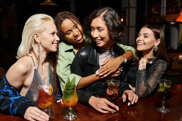 Cheerful african american woman hugging asian girlfriend in cocktail bar, glamorous hen party — Stock Photo