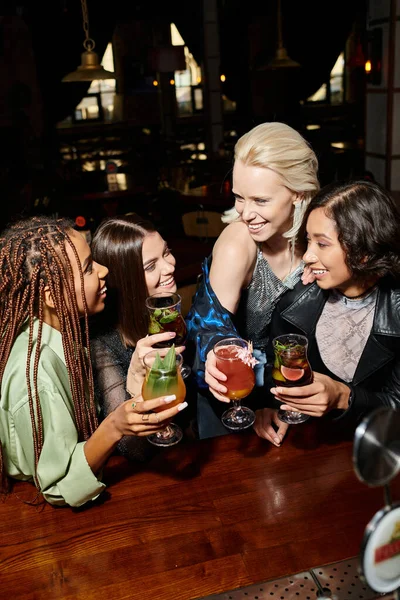 Modische multiethnische Freundinnen mit Cocktailgläsern im Gespräch in der Bar, stilvolle Atmosphäre — Stockfoto