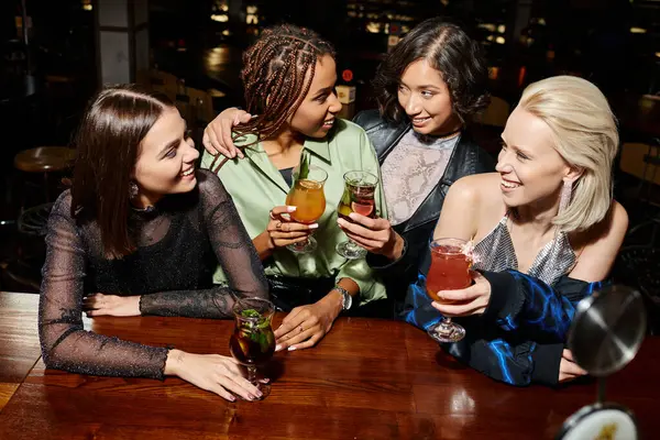 Модные мультикультурные подруги, пьющие коктейли во время отдыха в баре, гламурная вечеринка — стоковое фото