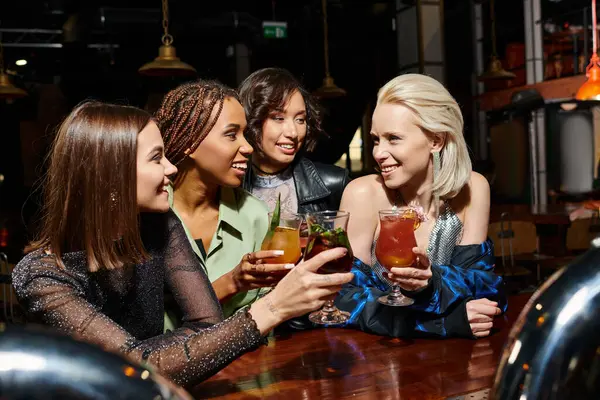 Amis féminins multiculturels élégants griller avec des cocktails pendant la fête de poule dans le bar, loisirs joyeux — Photo de stock