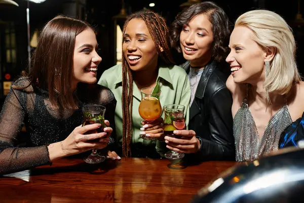 Cheerful multiethnic girlfriends with delicious cocktails talking during party in bar, leisure — Stock Photo
