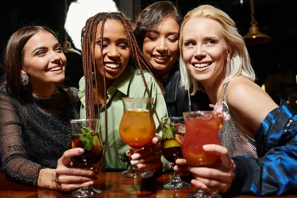 Joyful and elegant female friends holding glasses with delicious cocktails in bar, friendship — Stock Photo