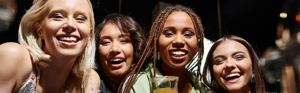 Groupe diversifié de copines multiethniques souriant à la caméra dans le bar de nuit, bannière horizontale — Photo de stock