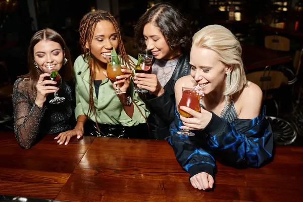 Happy multiracial fashionistas drinking delicious cocktails during party in bar, festive atmosphere — Stock Photo