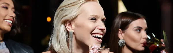Séduisante femme blonde souriant près du verre à cocktail et des copines multiethniques dans le bar, bannière — Photo de stock