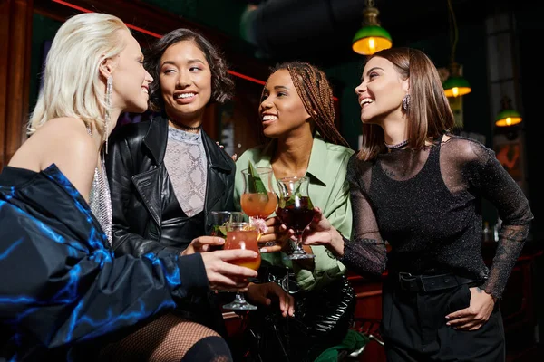 Glamourosa multirracial namoradas clinking copos de cocktail durante a festa no bar moderno, lazer — Fotografia de Stock