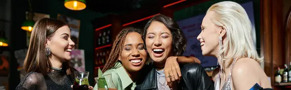 Cheerful multiracial girlfriends with cocktail glasses embracing and laughing in bar, banner — Stock Photo