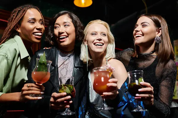 Glamorous multiethnic girlfriends with delicious cocktails laughing while having fun in bar — Stock Photo