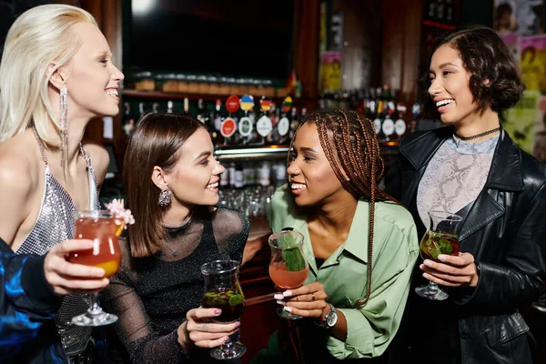 Young and elegant multiracial female friends with cocktails talking in bar, vibrant party time — Stock Photo